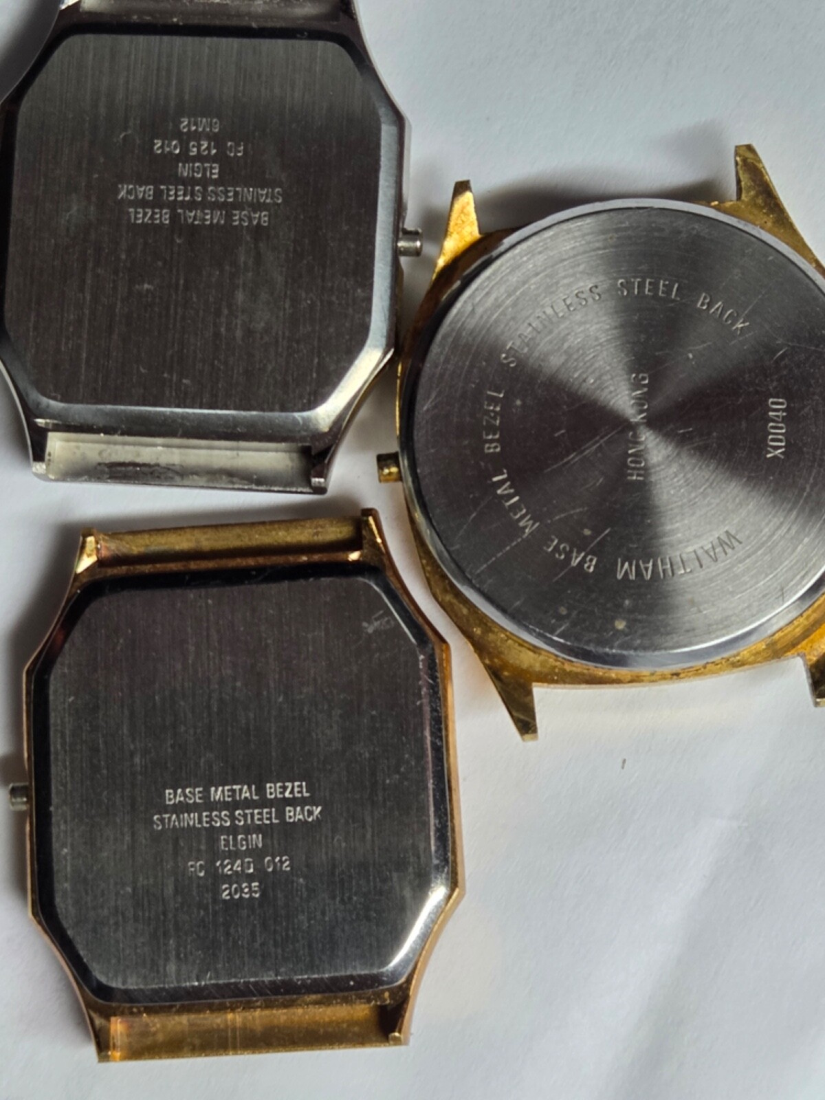 Four (4) men’s watch cases. 1980’s. For quartz movements. One has rotating bezel