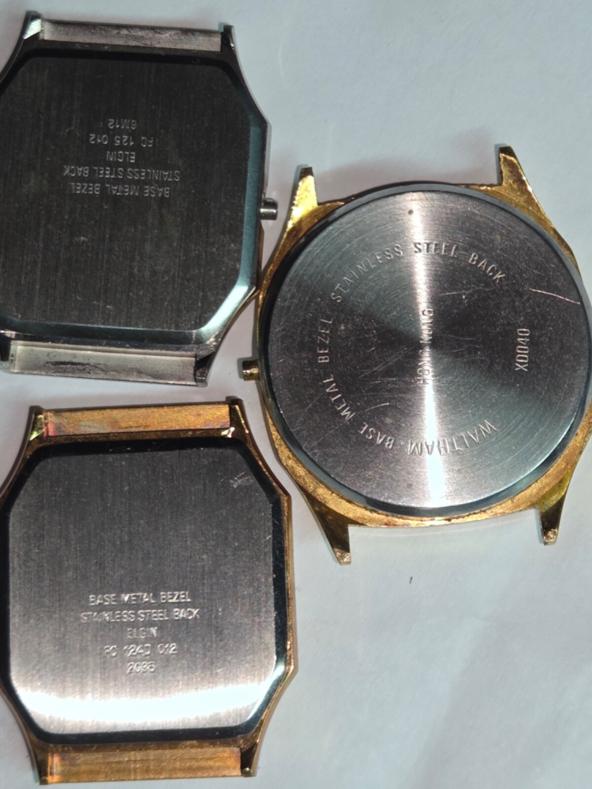 Four (4) men’s watch cases. 1980’s. For quartz movements. One has rotating bezel
